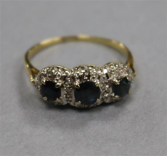 An 18ct gold and three stone sapphire ring, with diamond chip spacers, size R.